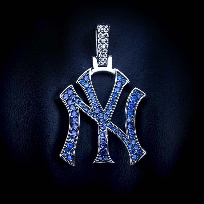 New York Yankees MLB logo pendant in 14k white gold plating with natural blue gemstones laid flat on textured surface.